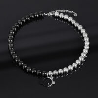 Collana con perle argento e nere e ciondolo a forma di gatto su sfondo scuro
