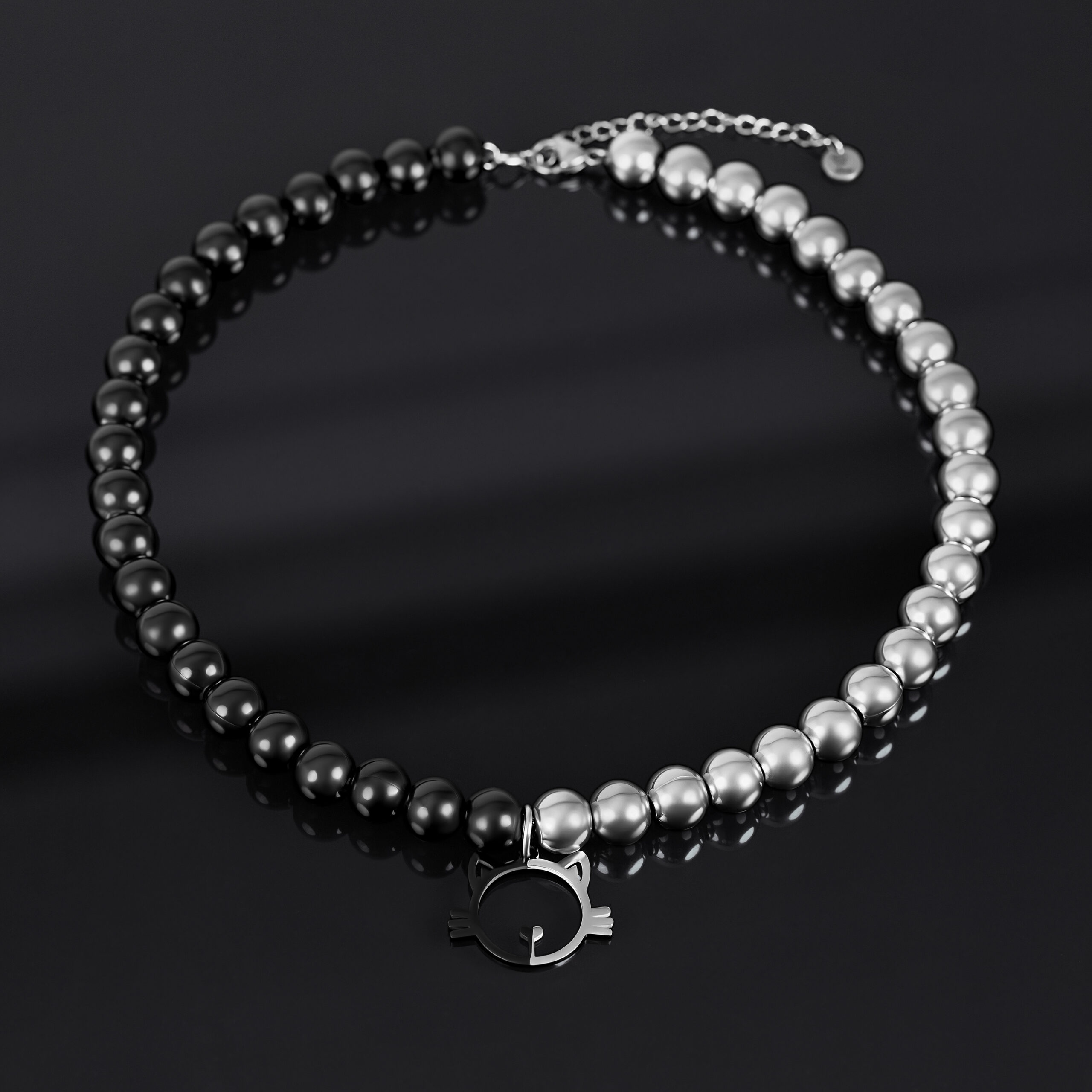 Collana con perle argento e nere e ciondolo a forma di gatto su sfondo scuro