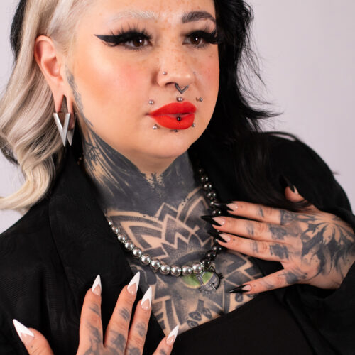 Donna con tatuaggi indossa Collana Bolle Gatto Argento Nero e piercing, sfondo nero