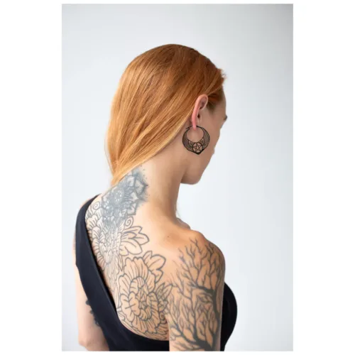 Donna con capelli rossi indossa orecchini pentagramma neri su sfondo bianco