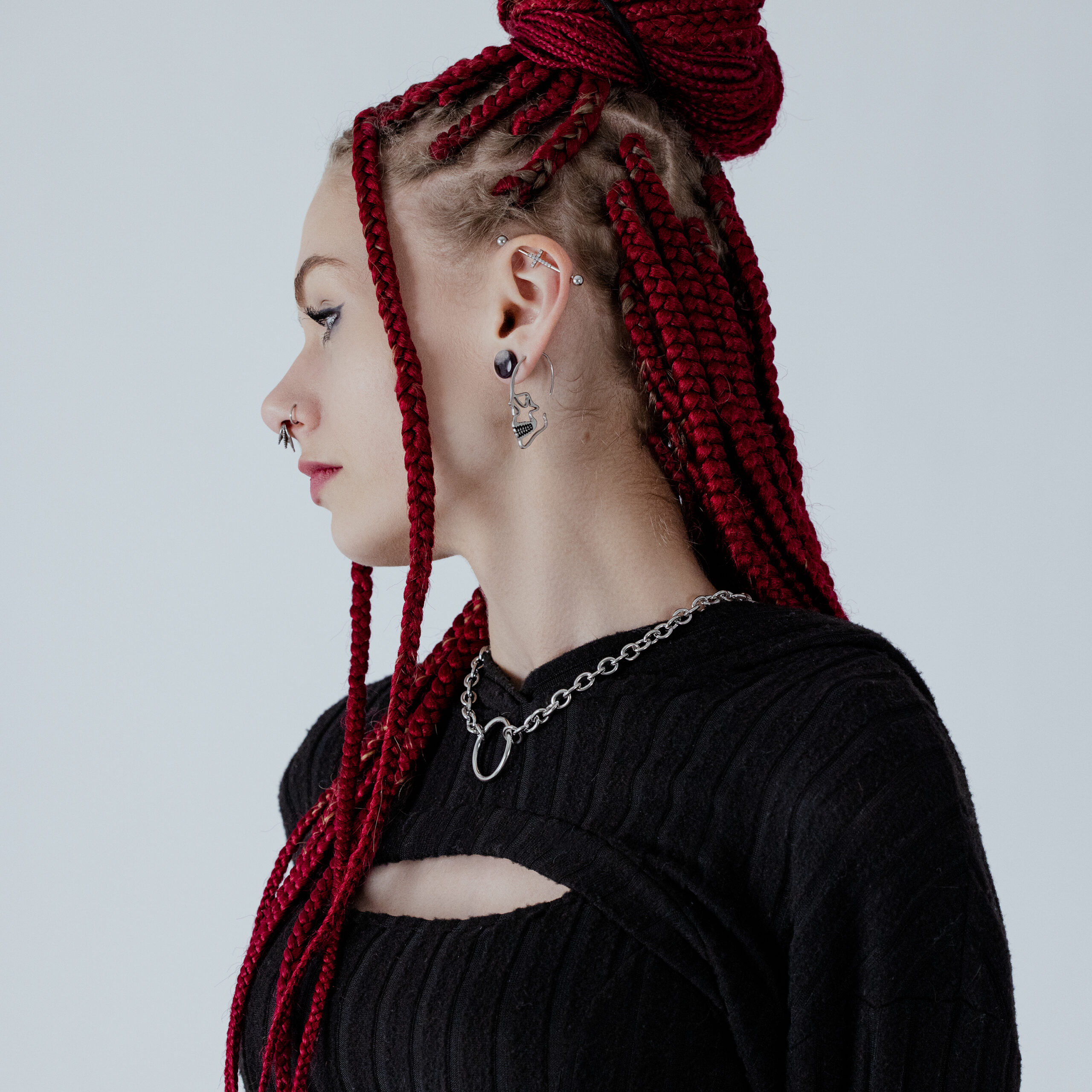 Donna con treccia rossa indossa un orecchino a forma di teschio in argento su sfondo chiaro