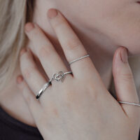 Anello Eye in acciaio chirurgico argento su mano femminile, design a cuore, primo piano