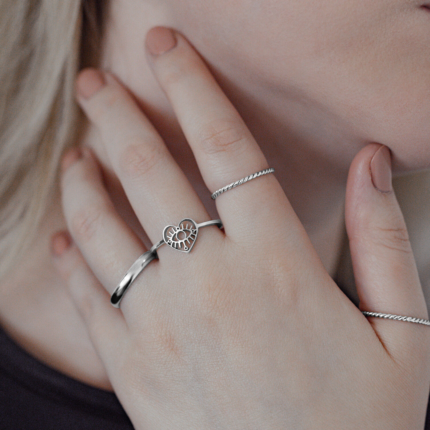 Anello Eye in acciaio chirurgico argento su mano femminile, design a cuore, primo piano