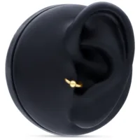 Anello a sfera in oro in piercing all'orecchio su sfondo nero