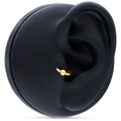 Anello a sfera in oro in piercing all'orecchio su sfondo nero