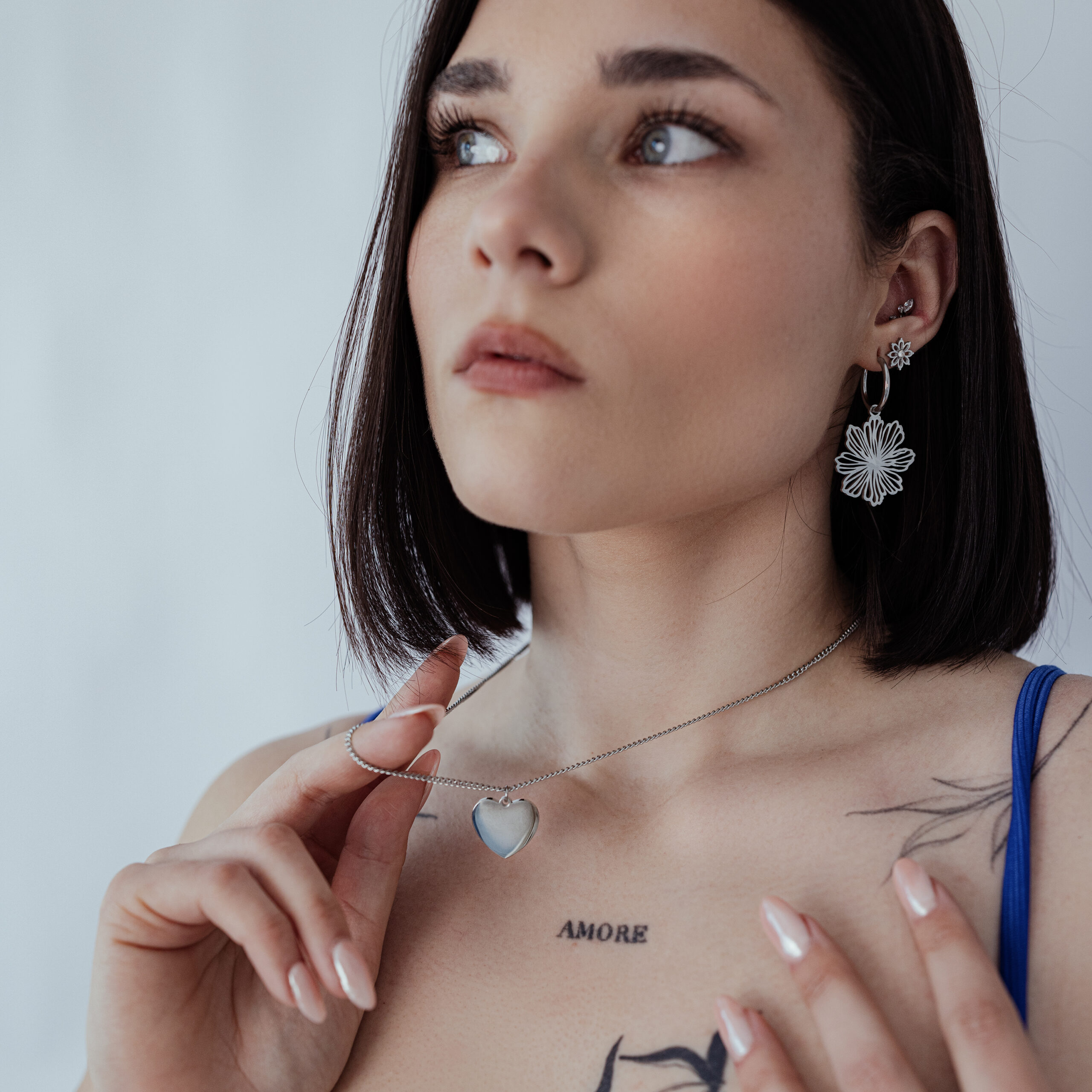 Donna indossa una collana d'argento con ciondolo a cuore personalizzabile su sfondo neutro