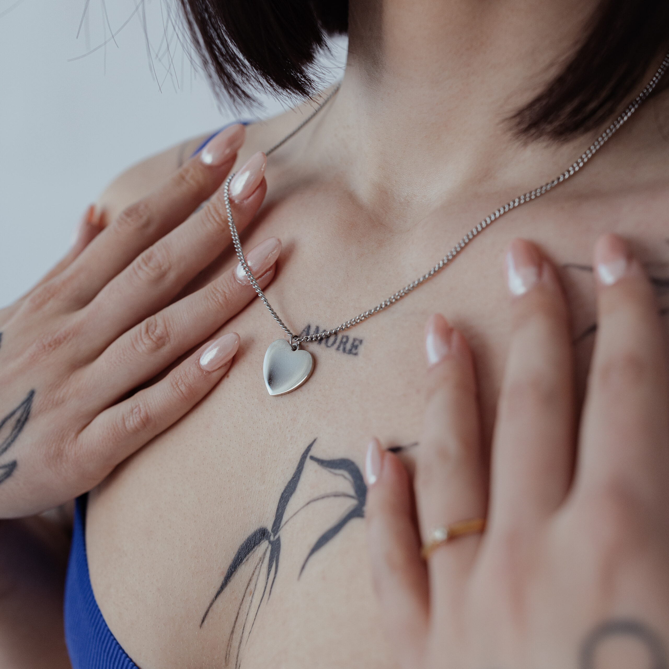 Collana argentata con ciondolo a cuore incidibile su pelle con tatuaggi