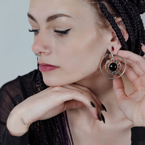 Donna con pesi per orecchie in ottone argentato e onice nero su sfondo chiaro
