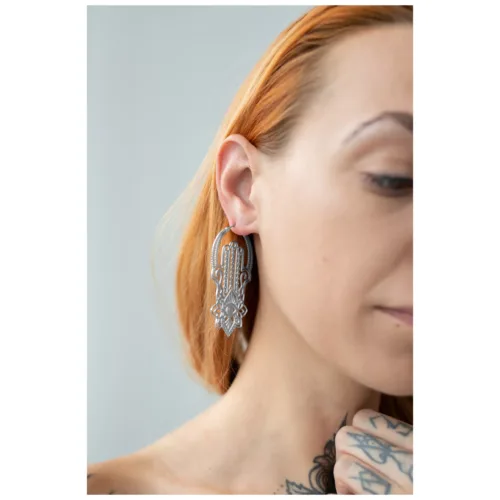 Donna con orecchini Khamsa Hoops in acciaio chirurgico argento su sfondo chiaro