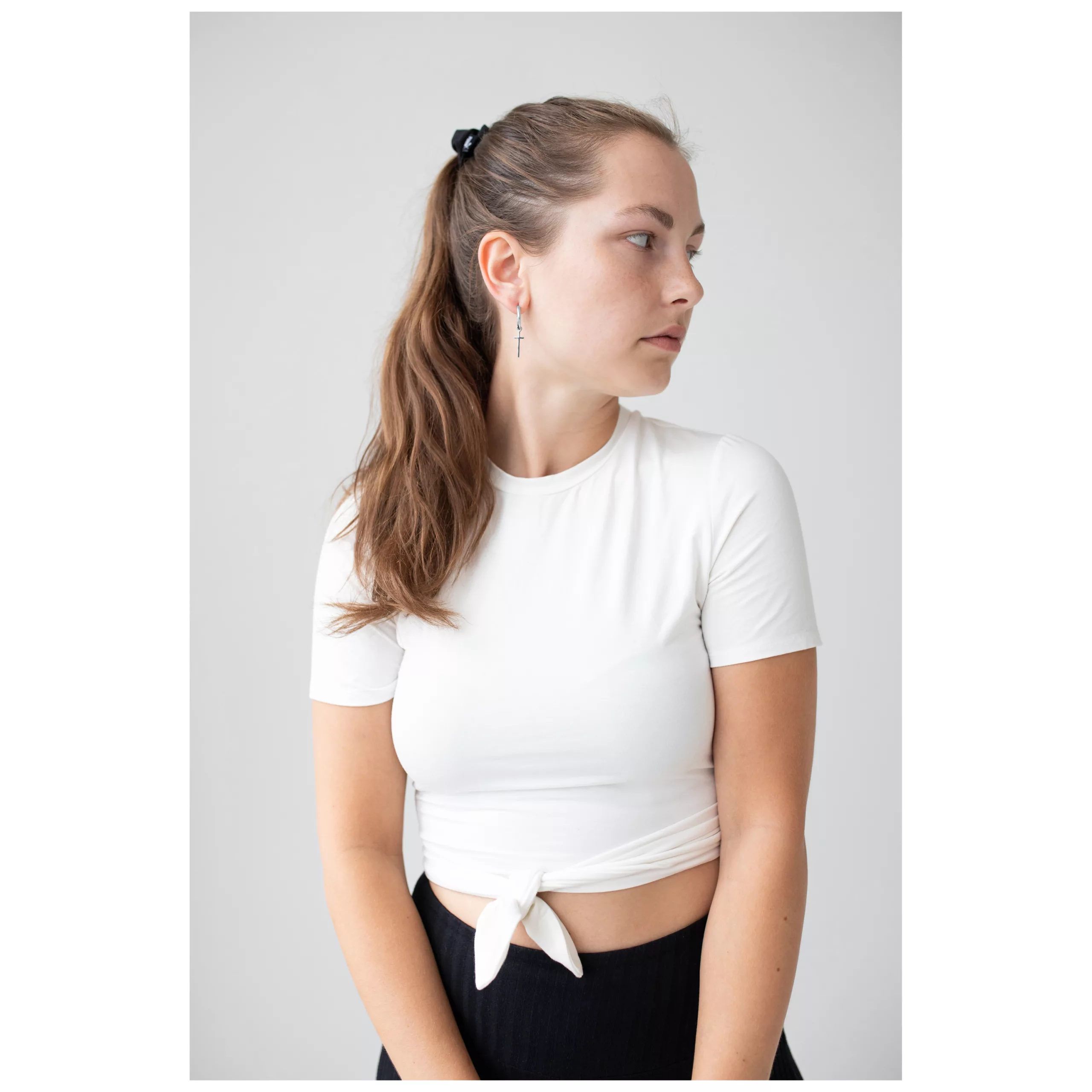Donna con orecchini Little Cross Hoops, top bianco, vista laterale