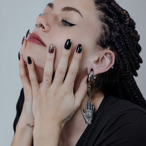 Donna con orecchino a forma di Mano di Hamsa in argento e oro, capelli intrecciati