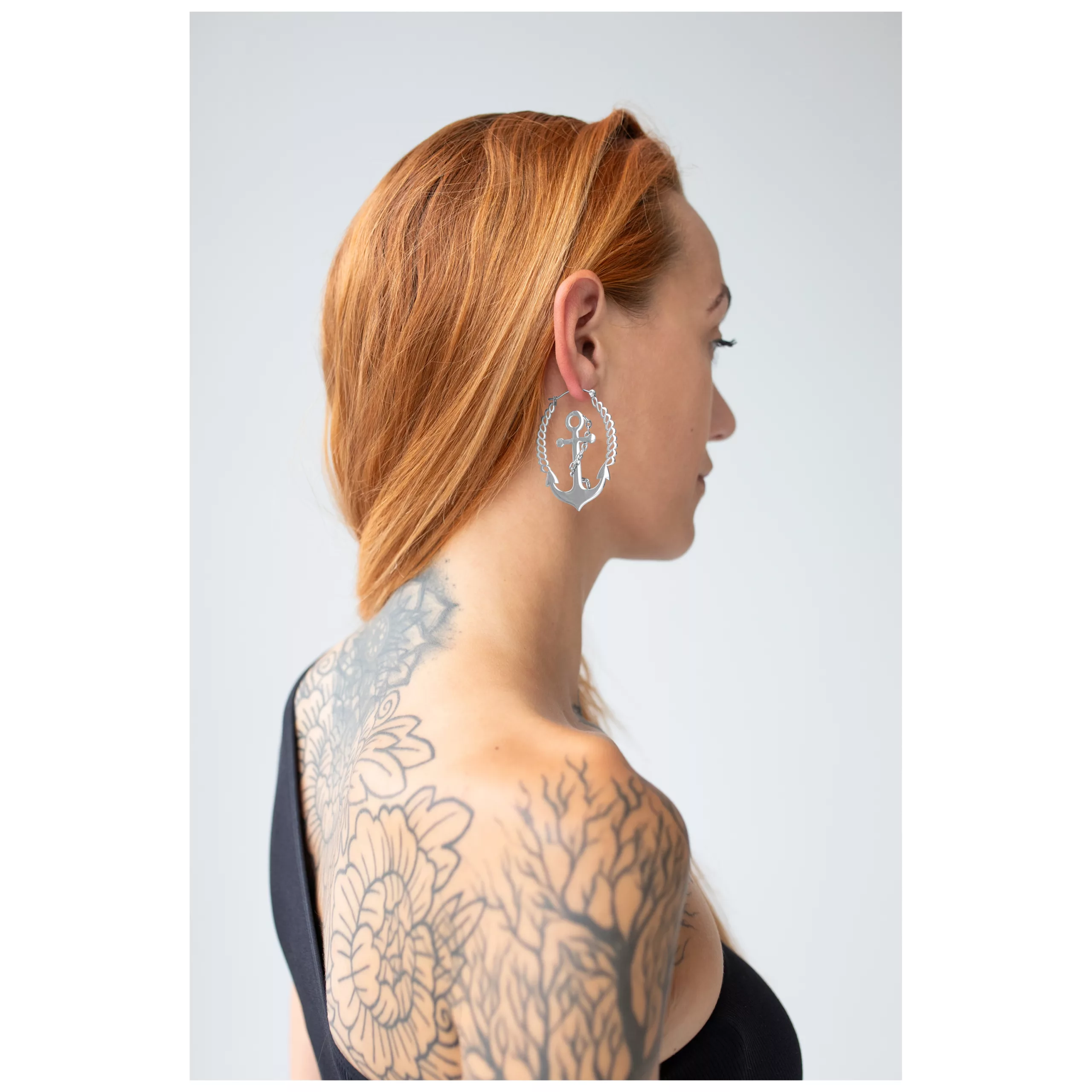 Donna con capelli rossi indossa orecchini a cerchio Chain Anchor in argento su sfondo chiaro