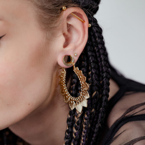 Primo piano di un orecchio con capelli intrecciati che indossa i goldene Ear Saddles Maori