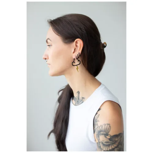 Donna con lunghi capelli scuri indossa orecchini neri e dorati a forma di nuvola