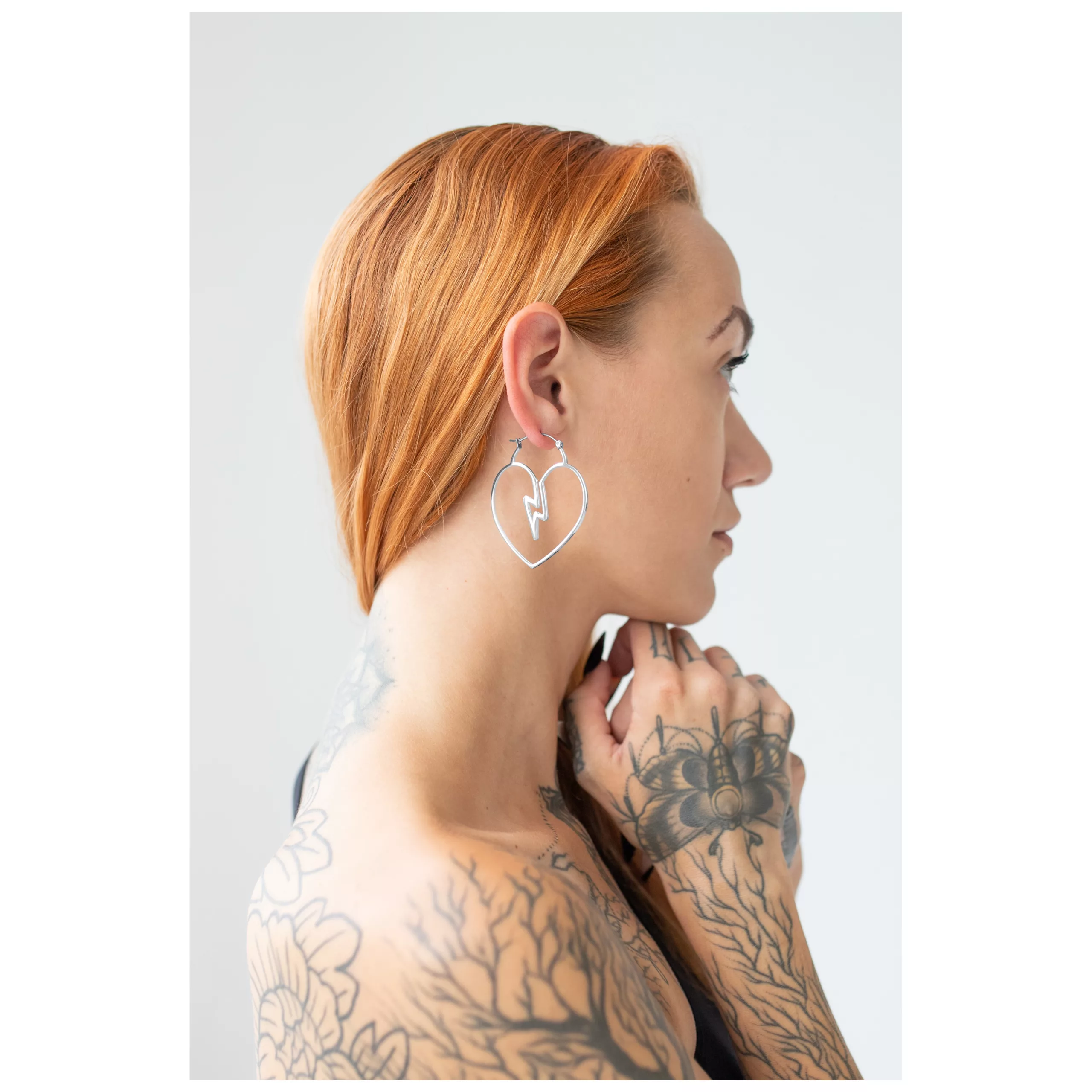Donna con orecchini a cuore in acciaio chirurgico argento, profilo laterale