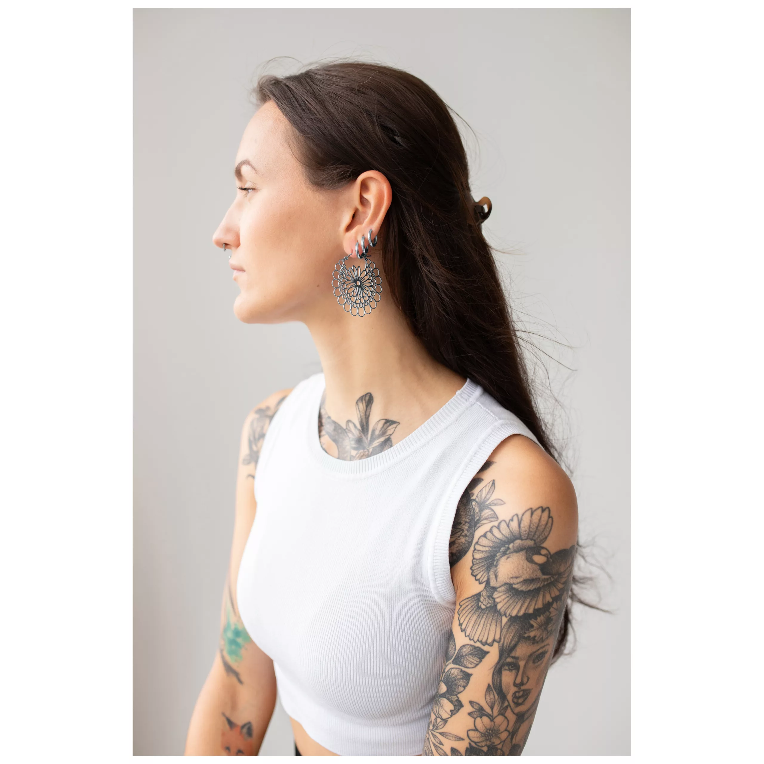 Donna con orecchini Daisy Hoops in nero e argento su sfondo grigio