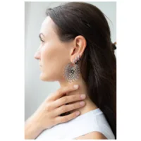 Donna con orecchini Daisy Hoops in acciaio chirurgico nero e argento.