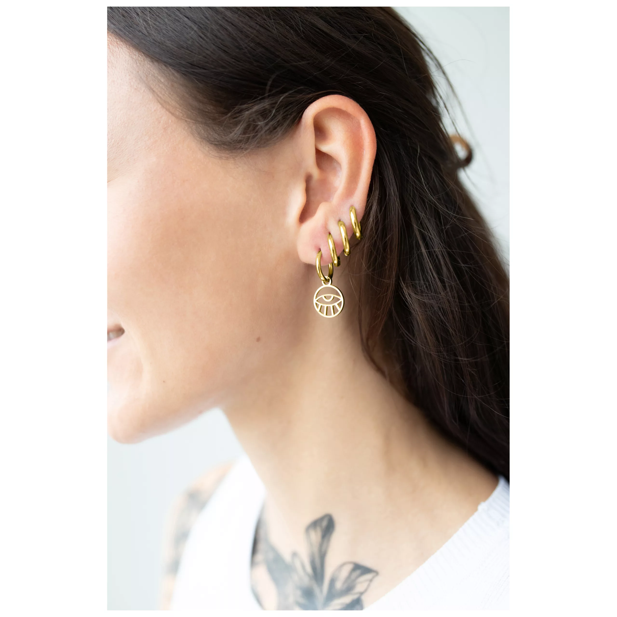 Little Eye Hoops dorati all'orecchio di una donna, lucenti ed eleganti