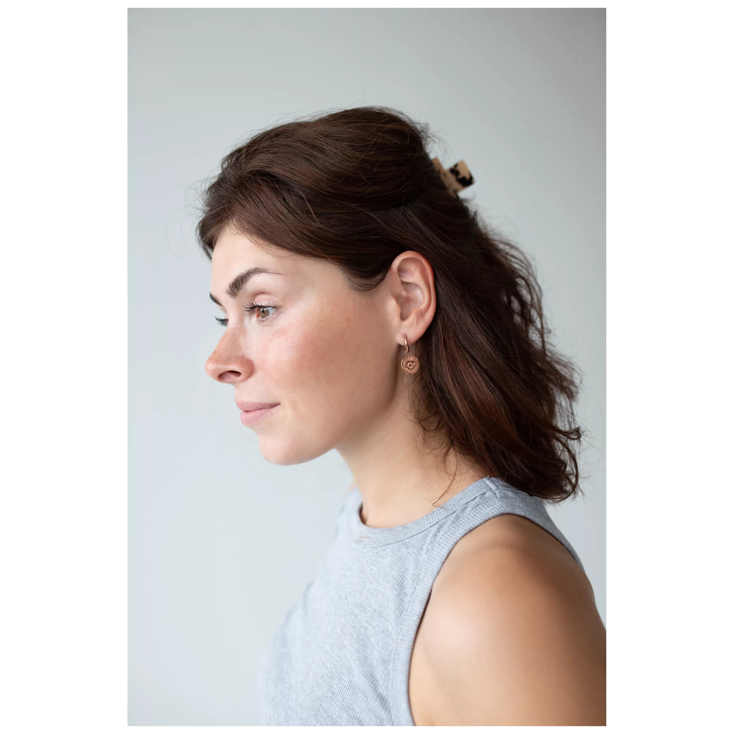 Donna con orecchini pendenti in oro rosa, design Luminous Eye, profilo laterale