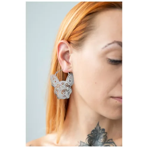Orecchini Bulldog in argento sull'orecchio di una donna con capelli chiari e tatuaggio