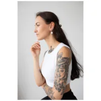 Donna con capelli lunghi indossa Little Smiley Hoops Orecchini, top bianco