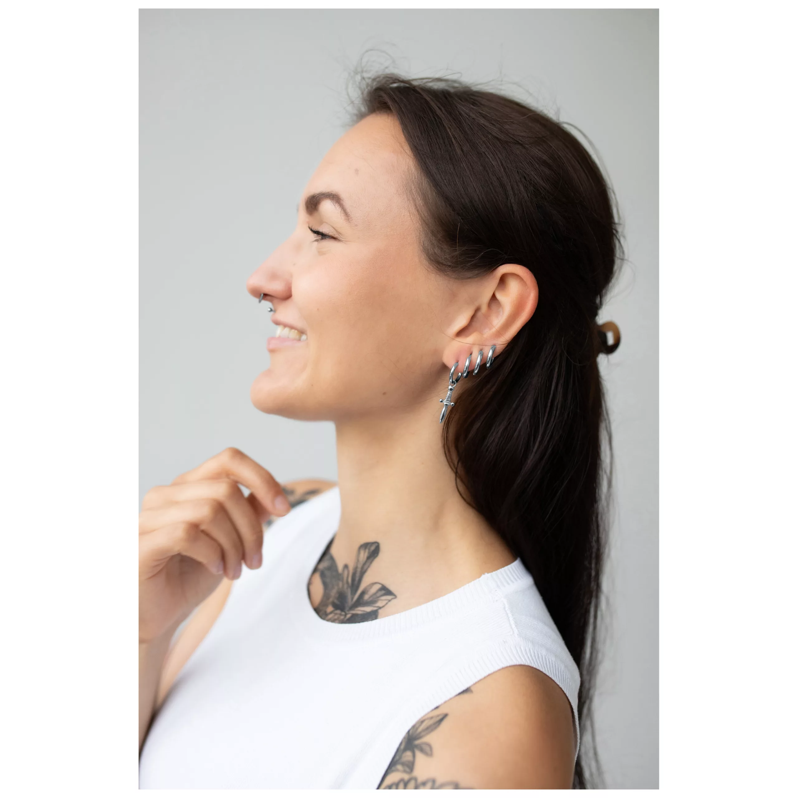 Donna con lunghi capelli scuri indossa orecchini Little Sword Hoops in argento su sfondo chiaro