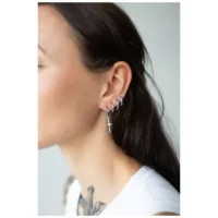 Orecchini d'argento a forma di spada su orecchio femminile su sfondo neutro