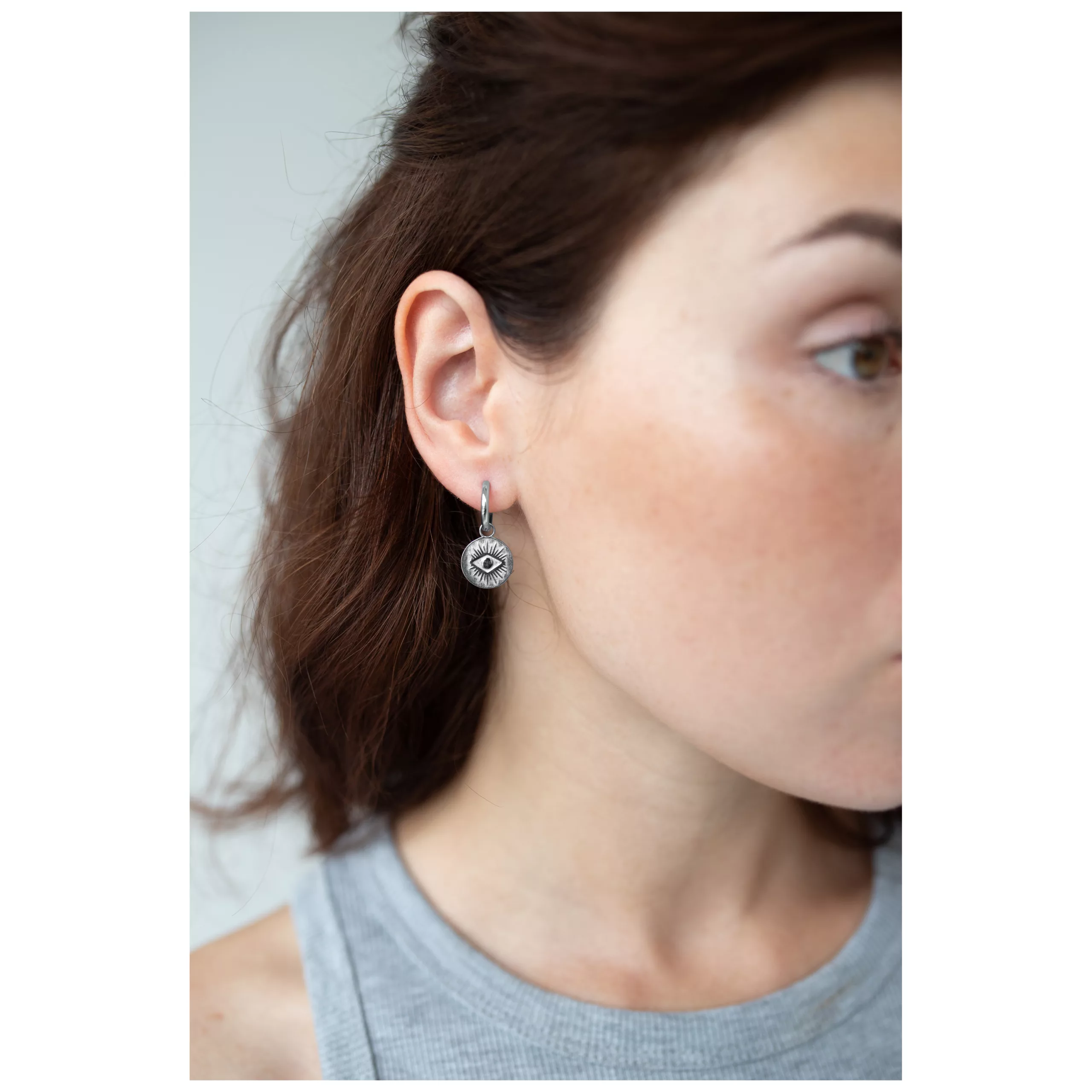 Donna che indossa orecchini d'argento con motivo a occhi, vista laterale