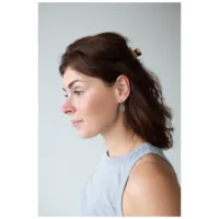 Donna con capelli castani indossa Little Luminous Eye Hoops, vista laterale