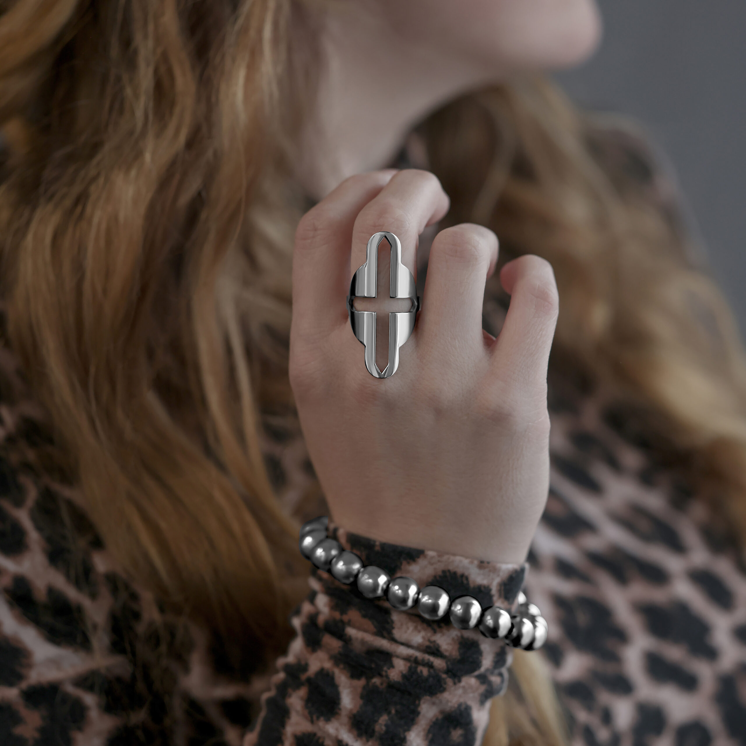 Grande anello con motivo a croce in acciaio chirurgico indossato su una mano