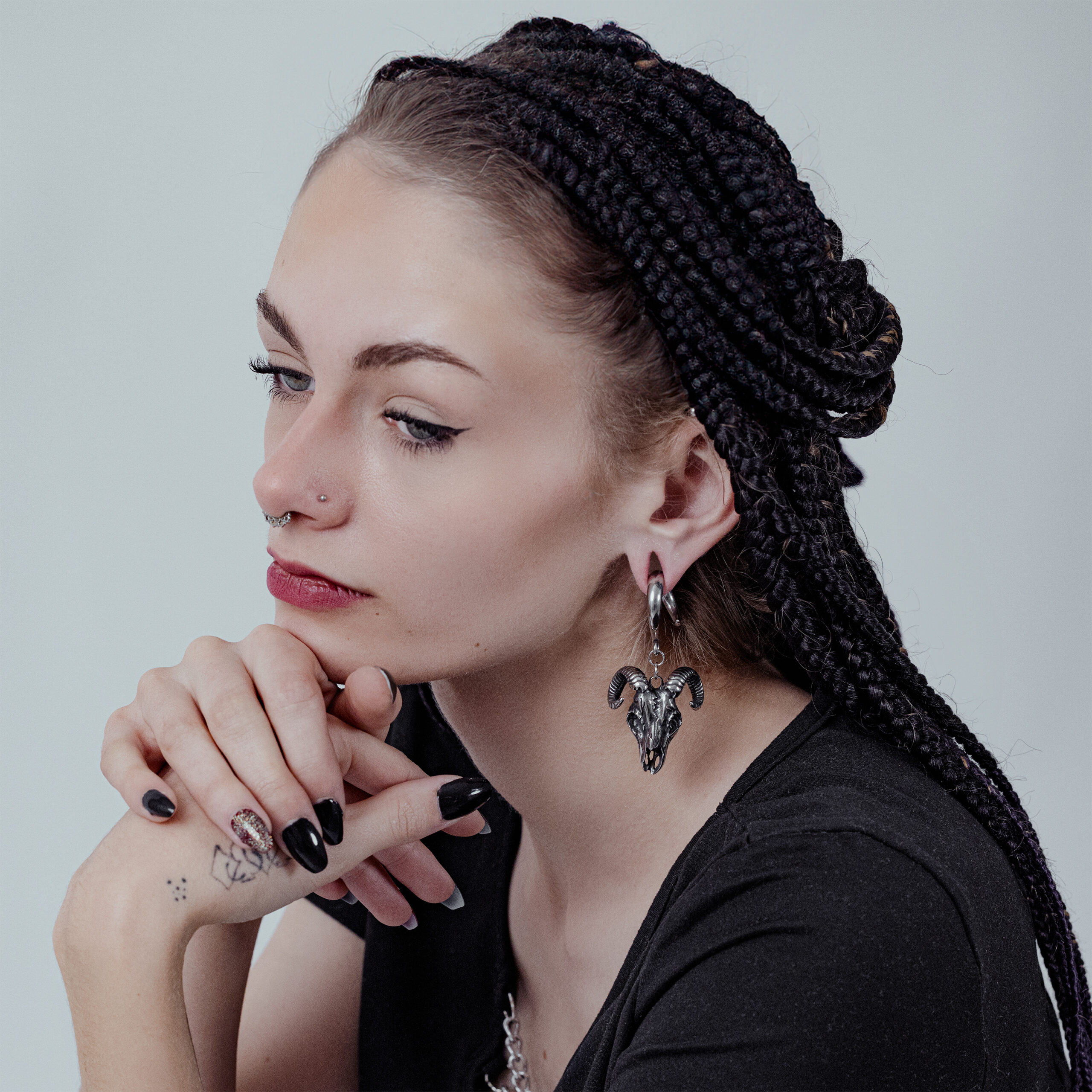 Donna con capelli intrecciati indossa pesi per orecchie Aries neri in acciaio chirurgico