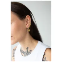Donna con orecchini Little Bulldog Hoops dorati e tatuaggi su sfondo bianco