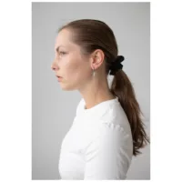 Donna con top bianco indossa orecchini a cerchio in argento con ciondolo a spada su sfondo grigio