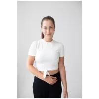 Donna indossa orecchini Little Cross Hoops in oro rosa su sfondo bianco