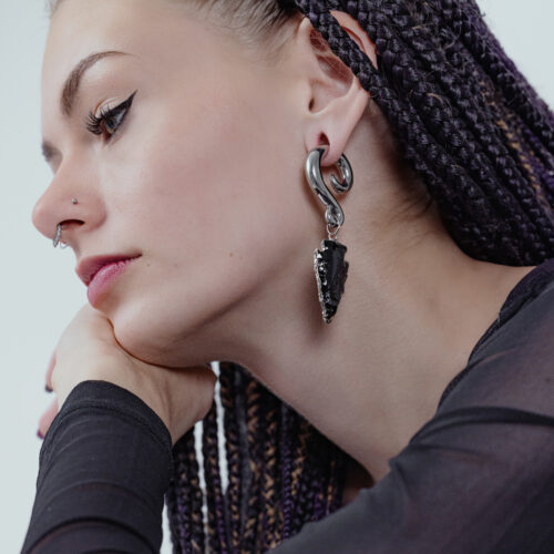 Donna con peso per orecchie pendente in ossidiana e argento, profilo laterale