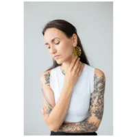 Donna con lunghi capelli neri indossa orecchini a cerchio Moon Eclipse dorati su sfondo grigio