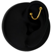 Catena piercing in oro 585 su un orecchio nero su sfondo nero