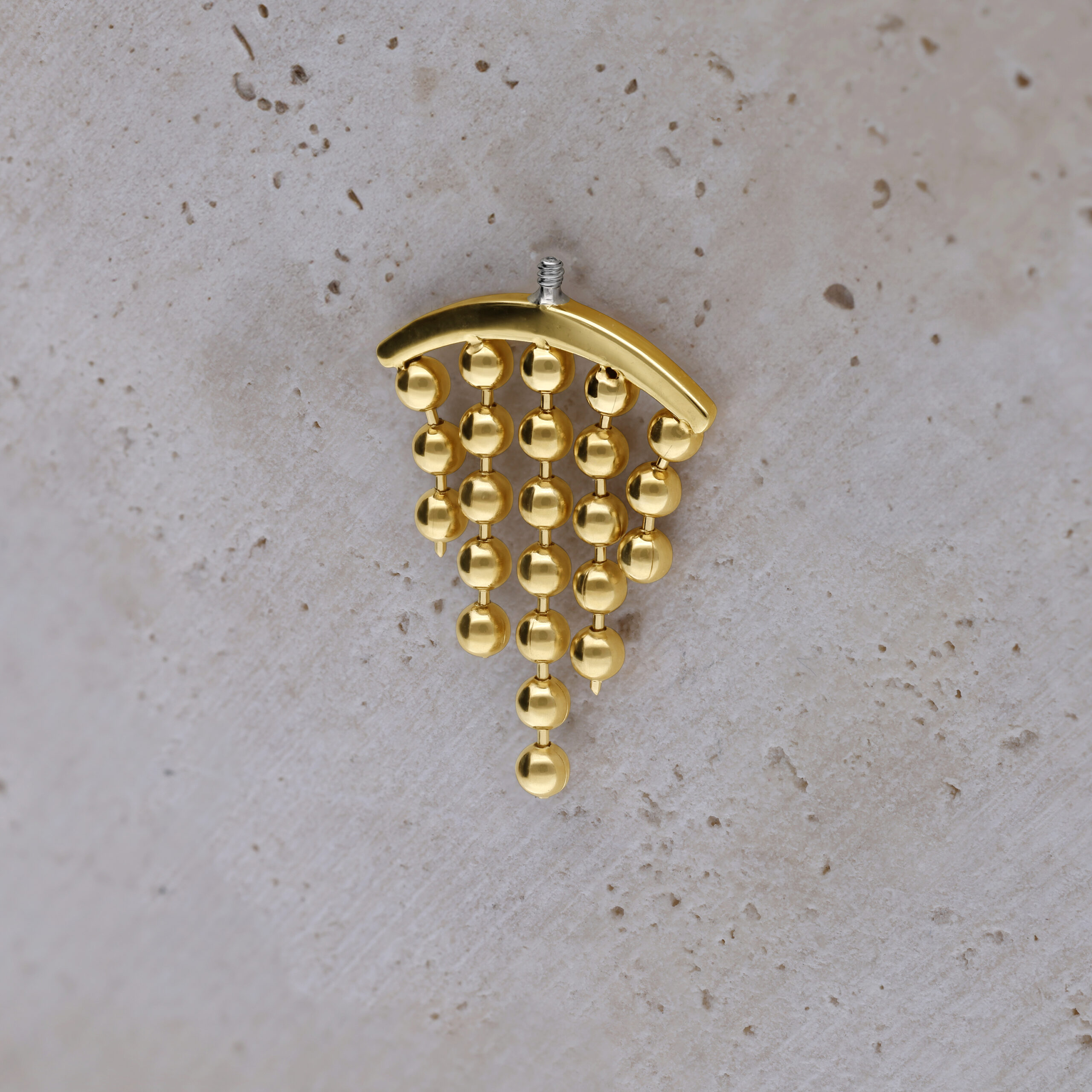 Punta per piercing helix color oro con sfere pendenti su sfondo chiaro