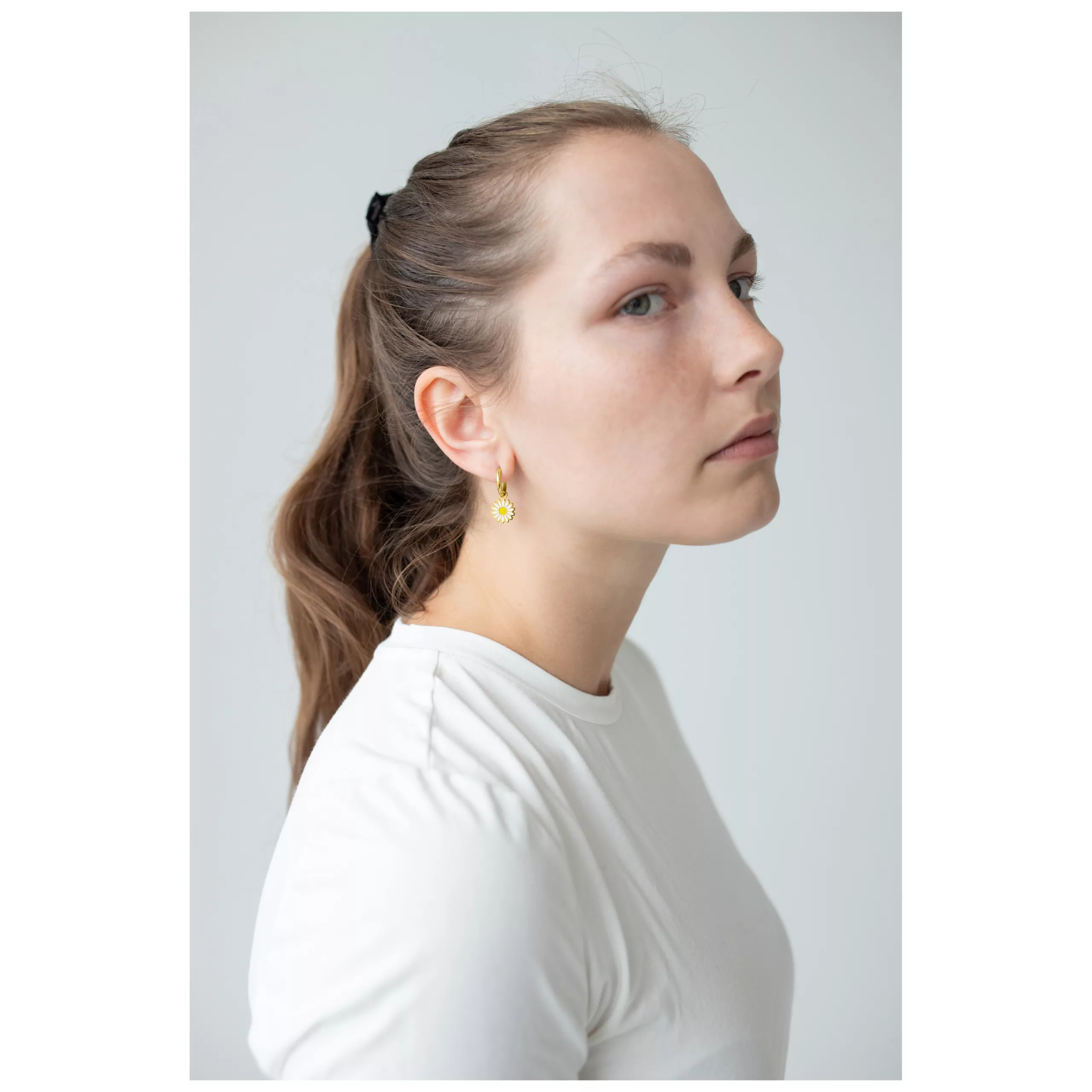 Donna con orecchini Little Daisy Hoops dorati su sfondo bianco
