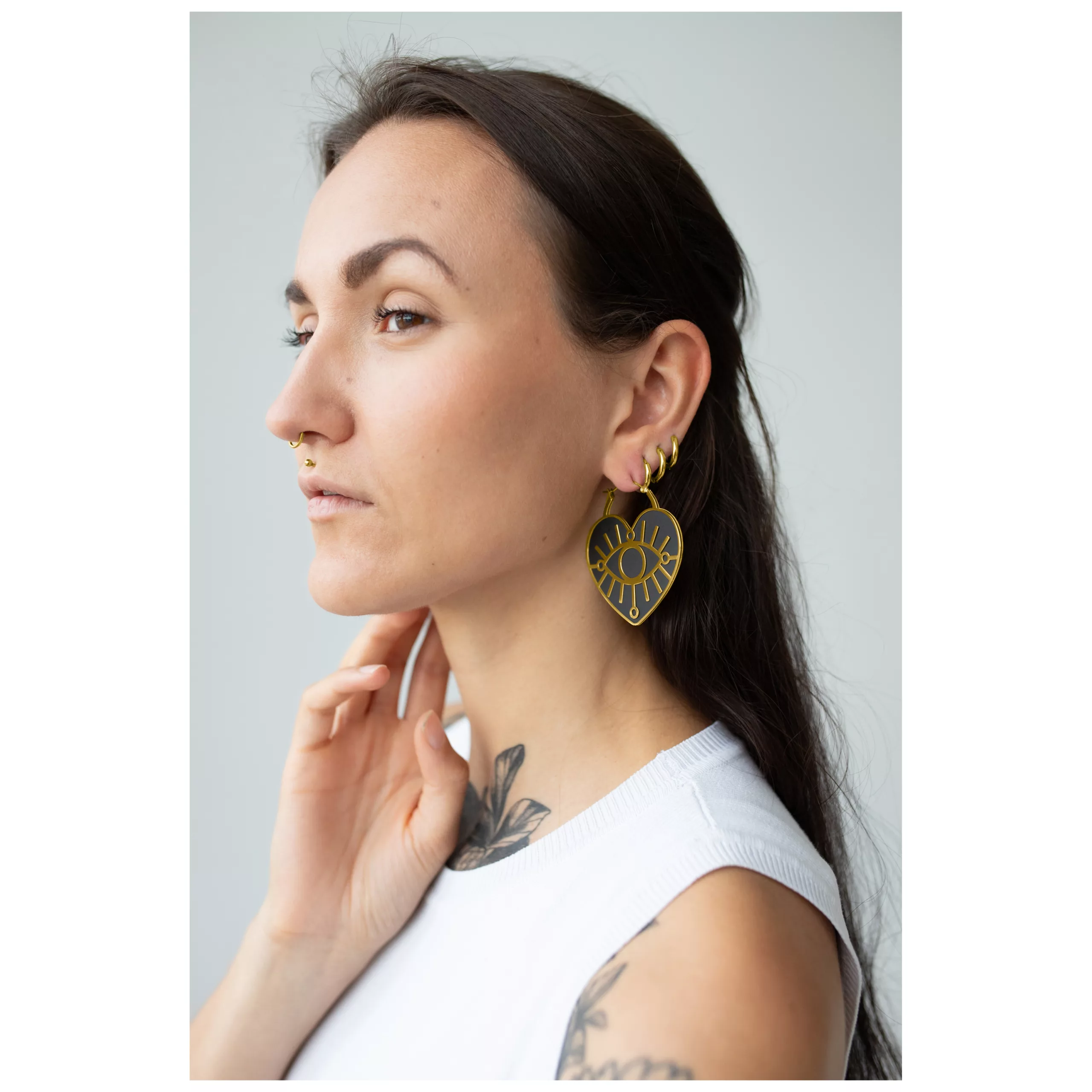 Donna con capelli lunghi indossa orecchini Soulmate Hoops dorati con chiusura a scatto.
