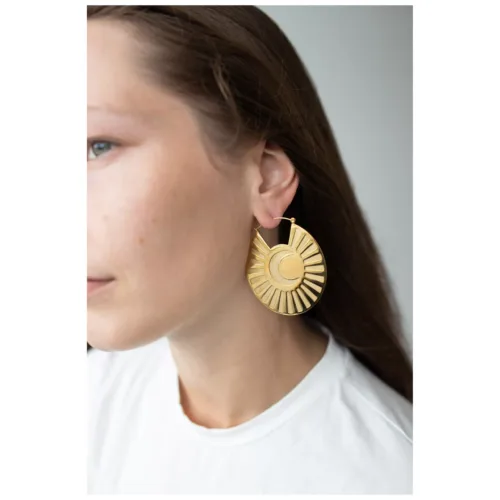 Donna con capelli lunghi indossa orecchini dorati a forma di sole