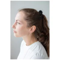 Donna con orecchini a cuore in oro rosa, capelli raccolti, maglia bianca