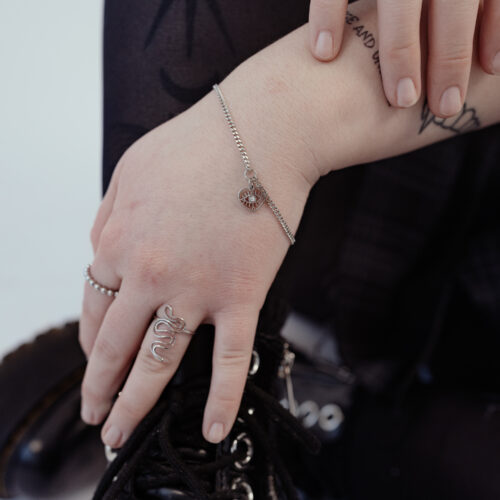 Bracciale delicato in argento con dettaglio a cuore, indossato al polso di una persona.