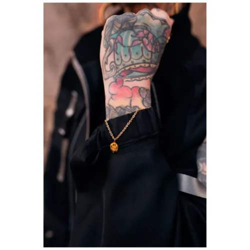 Braccialetto dorato con ciondolo Smiley su polso tatuato
