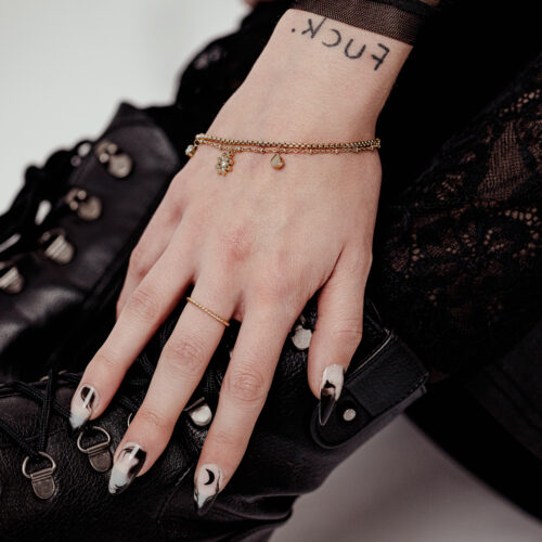 Mano con Little Floralis Braccialetto in Oro su stivale di pelle nero