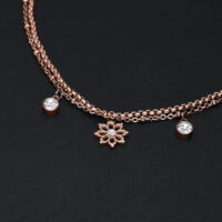 Bracciale in oro rosa con ciondolo a forma di fiore e cristalli chiari su sfondo nero