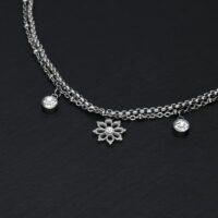 Bracciale in argento su sfondo nero con ciondoli floreali e cristalli