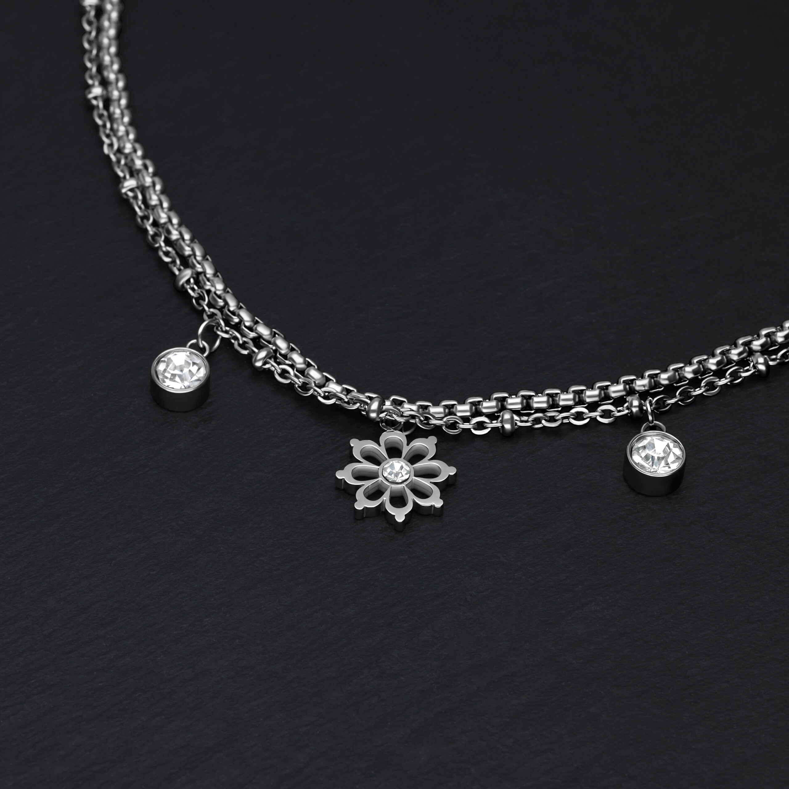Bracciale in argento su sfondo nero con ciondoli floreali e cristalli
