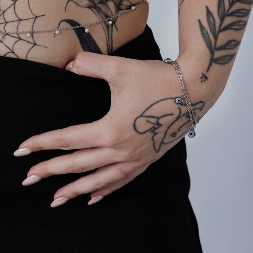 Braccialetto in argento con ciondolo Nazar al polso, mano tatuata
