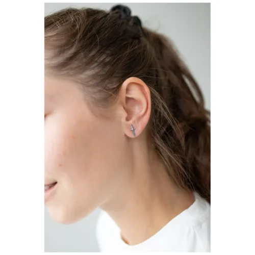 Orecchini a spada in argento sull'orecchio di una donna su sfondo chiaro